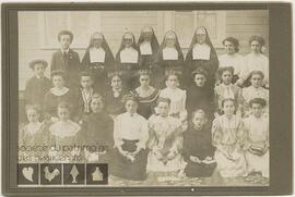 Portrait d’un groupe de vingt-cinq jeunes femmes et garçons et de cinq religieuses devant un bâtiment.